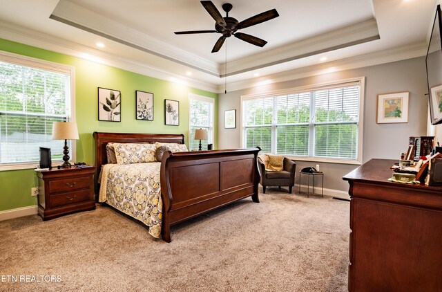 bedroom featuring baseboards, ornamental molding, light carpet, and a tray ceiling