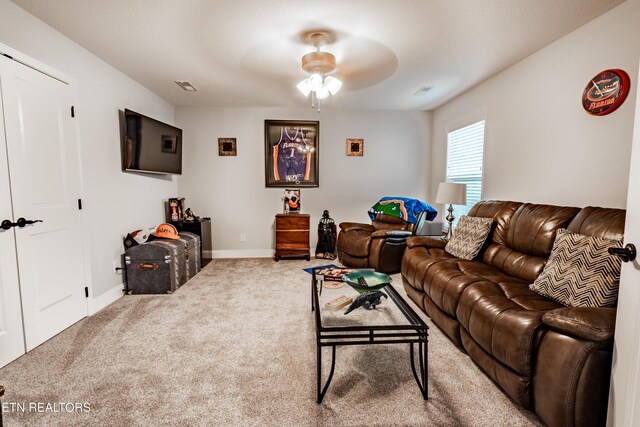 carpeted living room with ceiling fan and baseboards