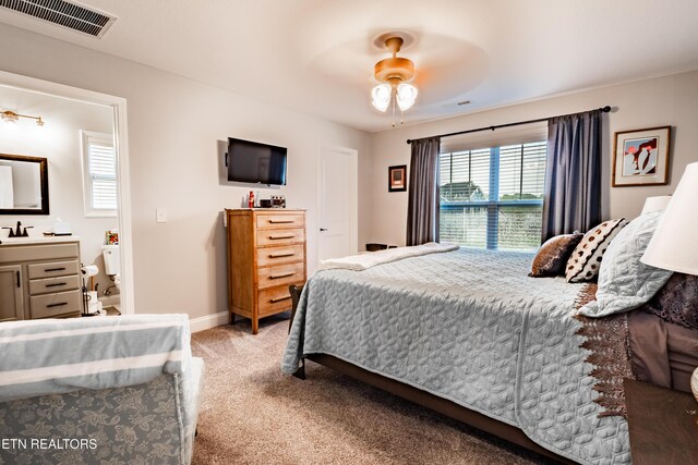 carpeted bedroom with baseboards, visible vents, a ceiling fan, and a sink
