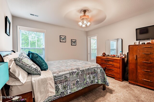 bedroom with a ceiling fan, visible vents, and light colored carpet