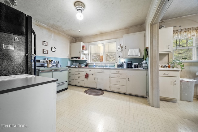 kitchen featuring white cabinets, white electric range oven, a textured ceiling, and a sink