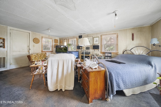 carpeted bedroom featuring wood walls, a textured ceiling, and visible vents