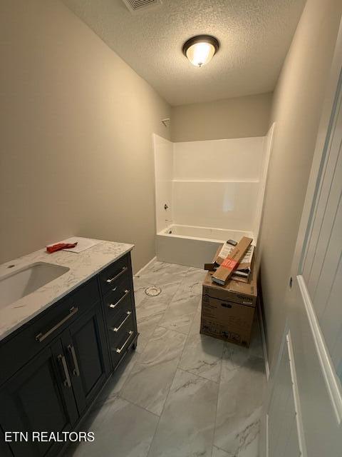 515 Hillcrest St, Clinton, TN 37716 - full bath with a textured ceiling, vanity, marble finish flooring, and washtub / shower combination