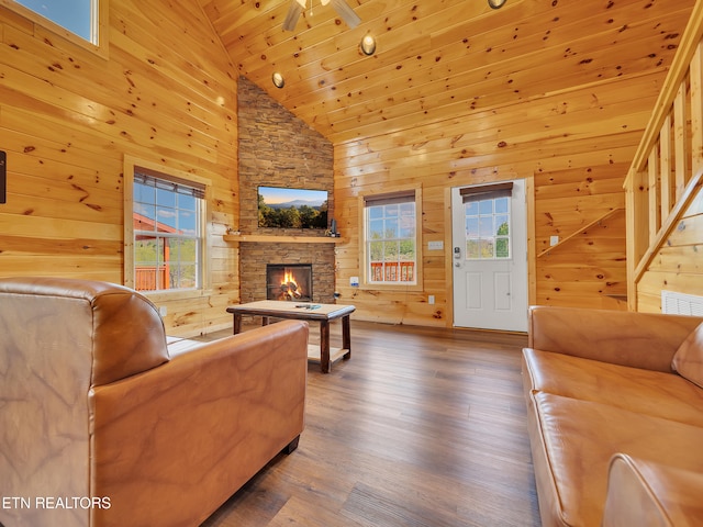 living area with high vaulted ceiling, a stone fireplace, wooden ceiling, wood finished floors, and wooden walls