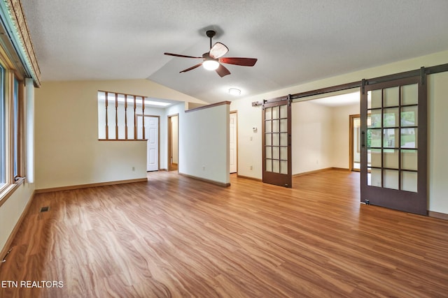 214 Snead Dr, Crossville, TN 38558 - empty room featuring lofted ceiling, ceiling fan, a barn door, and wood finished floors
