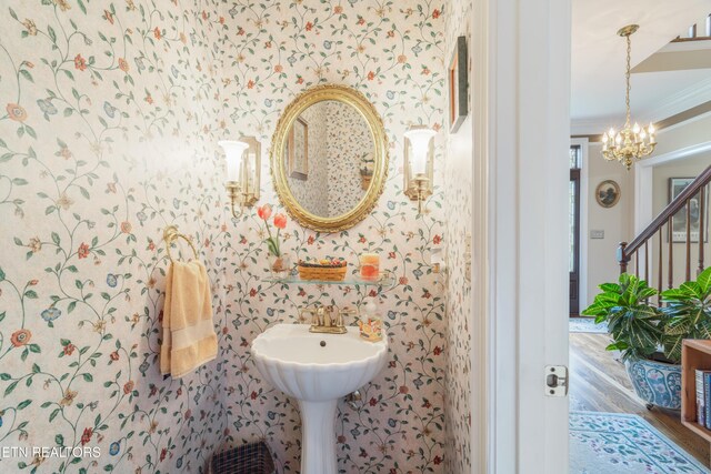 bathroom with ornamental molding, wallpapered walls, wood finished floors, and a chandelier