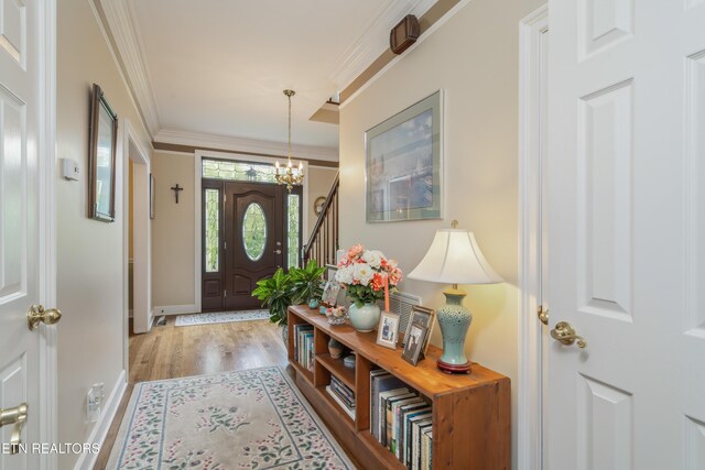 foyer entrance with baseboards, a chandelier, ornamental molding, and wood finished floors