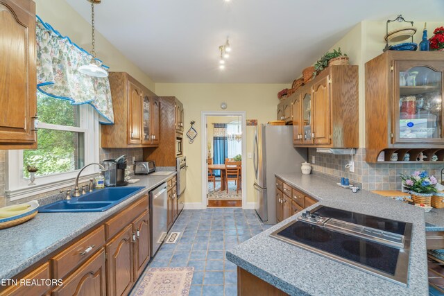 kitchen with a sink, decorative backsplash, brown cabinetry, and stainless steel appliances