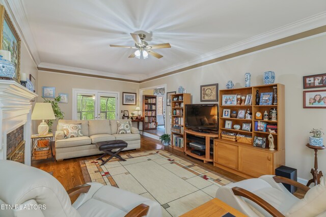 living room with a ceiling fan, ornamental molding, wood finished floors, and a tile fireplace