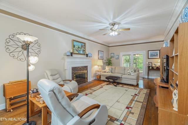 living room with crown molding, a ceiling fan, wood finished floors, and a fireplace