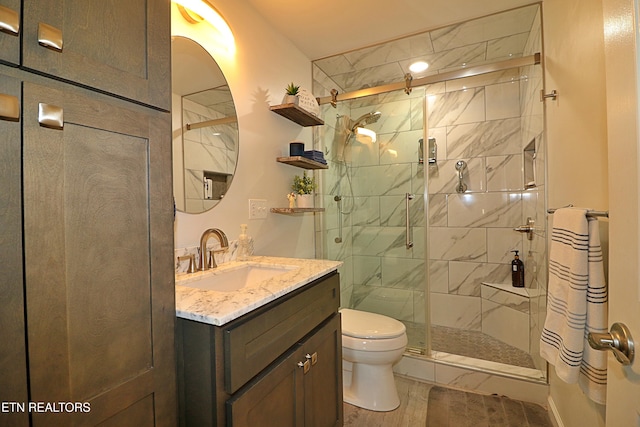 bathroom featuring vanity, a stall shower, toilet, and wood finished floors