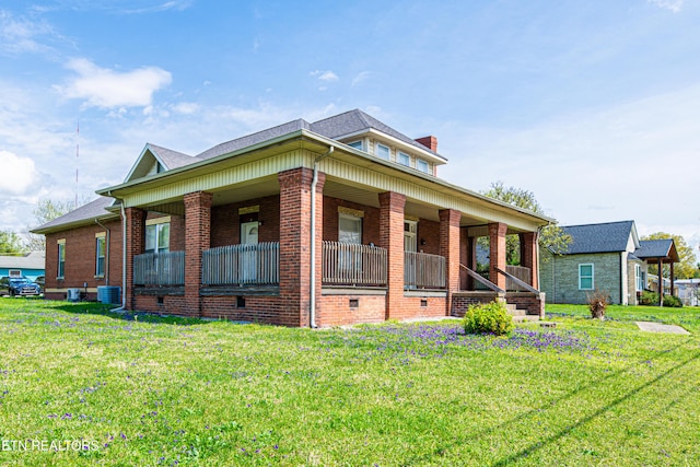 view of front of house with brick siding, a porch, a front lawn, and a chimney
