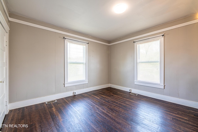 empty room with wood finished floors, baseboards, and visible vents