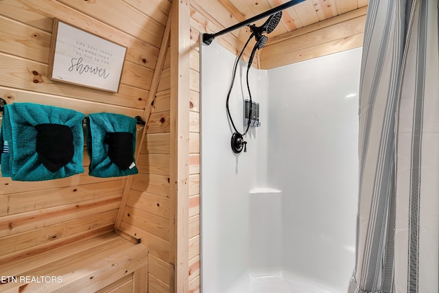 full bathroom with a shower stall and wooden walls