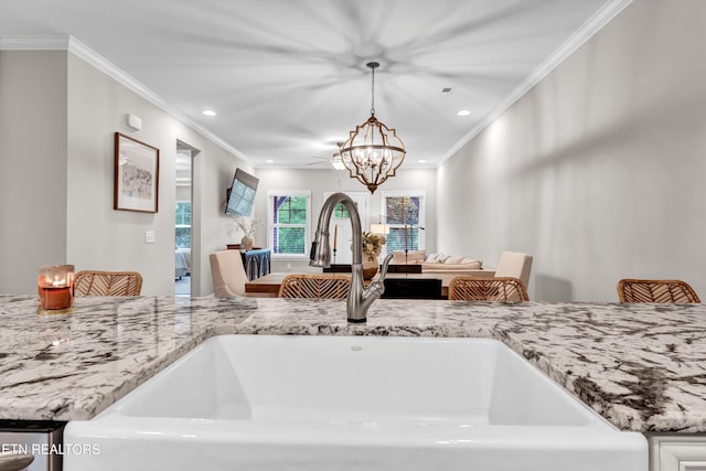interior details featuring light stone countertops, a sink, a chandelier, and crown molding
