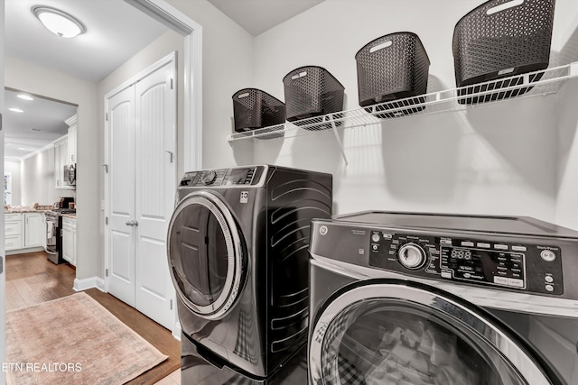 washroom with wood finished floors, washer and dryer, and laundry area