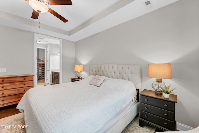 bedroom with wood finished floors, ceiling fan, baseboards, ensuite bath, and visible vents