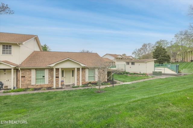 7914 Gleason Dr Unit 1145, Knoxville, TN 37919 - view of front of house with an outdoor structure, roof with shingles, fence, a front lawn, and brick siding