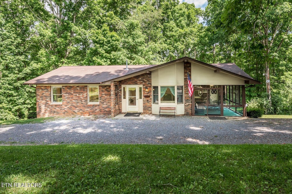 1211 Old Hollow Rd, Loudon, TN 37774 - view of front facade with brick siding, a front lawn, a sunroom, and roof with shingles