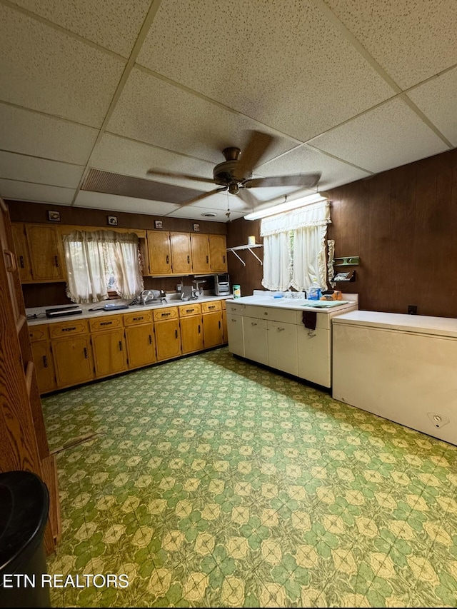 1211 Old Hollow Rd, Loudon, TN 37774 - kitchen featuring tile patterned floors, brown cabinetry, a drop ceiling, a ceiling fan, and wooden walls