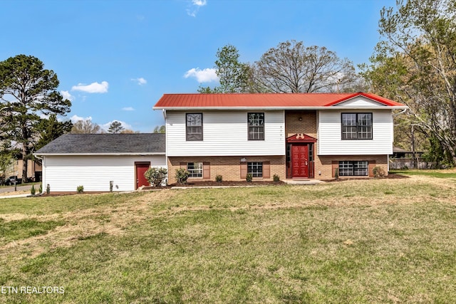 bi-level home featuring brick siding, a front yard, and metal roof