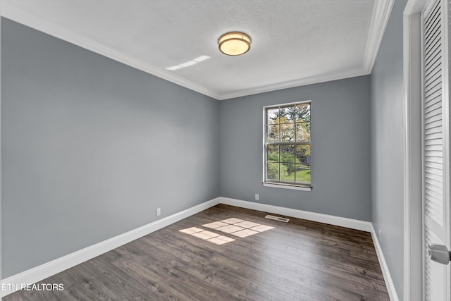 empty room with dark wood-type flooring, visible vents, baseboards, and ornamental molding
