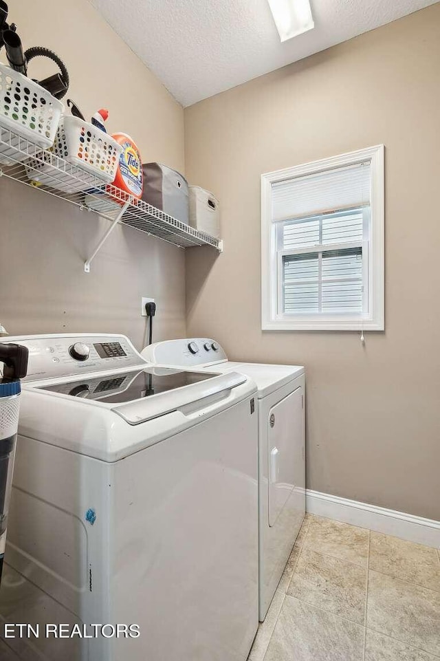 laundry room with laundry area, a textured ceiling, tile patterned floors, baseboards, and washer and clothes dryer