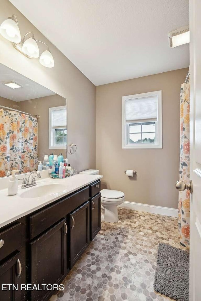 bathroom with toilet, vanity, and baseboards