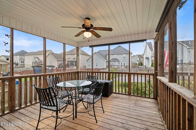 sunroom / solarium with a wealth of natural light, a residential view, outdoor dining area, and a ceiling fan