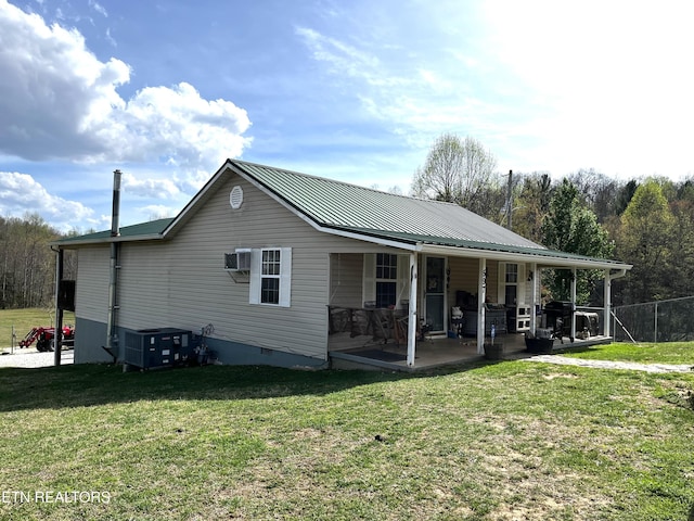 back of property with central AC, crawl space, a lawn, fence, and metal roof