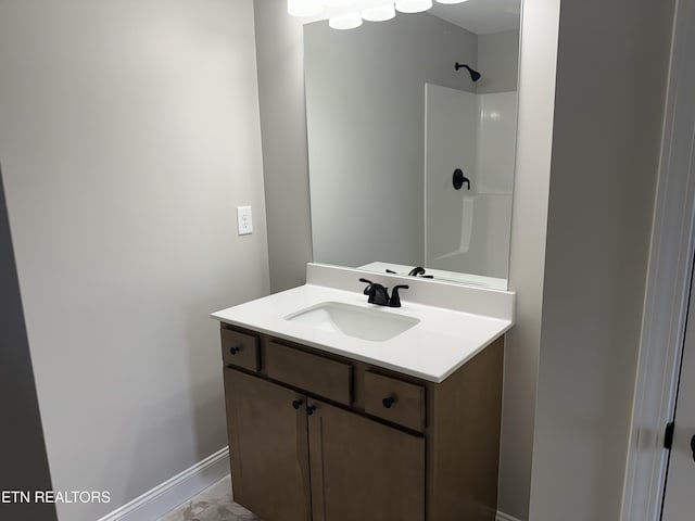 bathroom featuring vanity, baseboards, and walk in shower