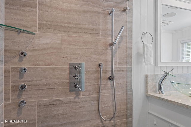 bathroom featuring tiled shower and vanity