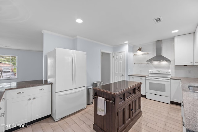 kitchen featuring visible vents, wall chimney exhaust hood, white appliances, white cabinetry, and backsplash