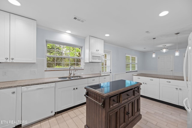 kitchen featuring visible vents, a sink, white appliances, a healthy amount of sunlight, and decorative backsplash