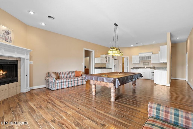 game room featuring billiards, wood finished floors, a tile fireplace, a sink, and recessed lighting