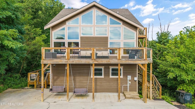 rear view of house featuring a patio area, stairway, and a shingled roof