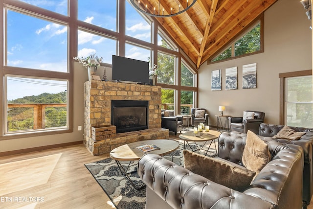 living room with a healthy amount of sunlight, a stone fireplace, wooden ceiling, and wood finished floors