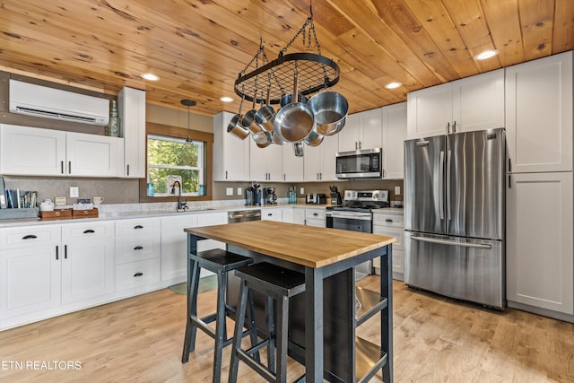 kitchen with butcher block countertops, appliances with stainless steel finishes, a wall mounted AC, and wood ceiling