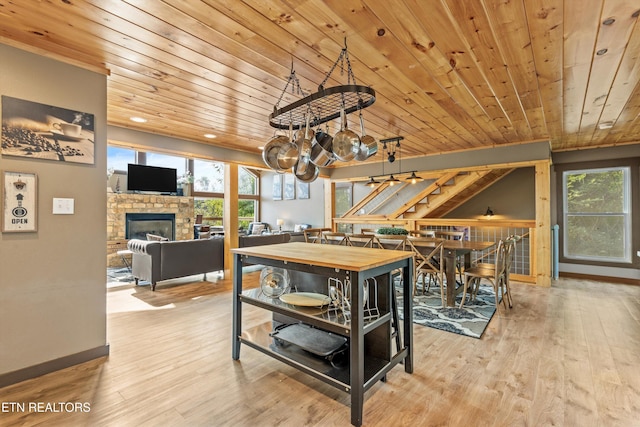 dining area featuring a chandelier, wood finished floors, a glass covered fireplace, and stairs