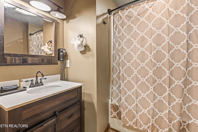 bathroom featuring a shower with shower curtain, vanity, and a textured wall