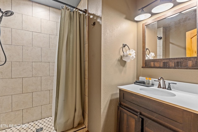 bathroom with tiled shower and vanity