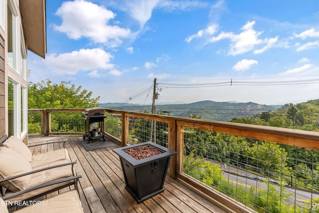 wooden deck featuring a fire pit, grilling area, and a mountain view