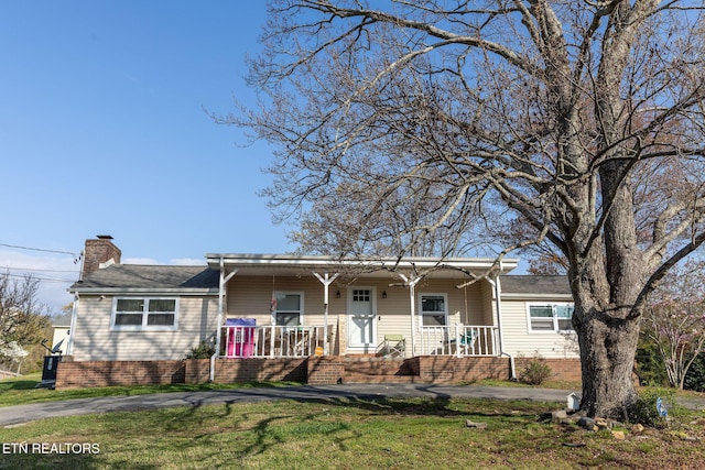 single story home with a front yard, a porch, and a chimney