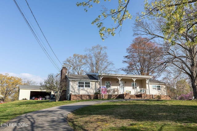 ranch-style house featuring a porch, curved driveway, a front lawn, and a chimney