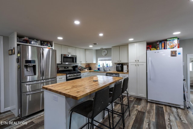 kitchen featuring appliances with stainless steel finishes, wood counters, dark wood-style floors, and white cabinets