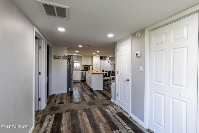 corridor with dark wood-style flooring, visible vents, and recessed lighting