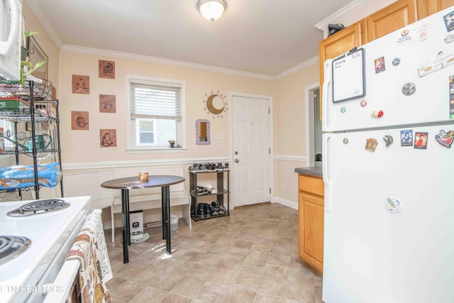 kitchen with range, freestanding refrigerator, light brown cabinets, and ornamental molding