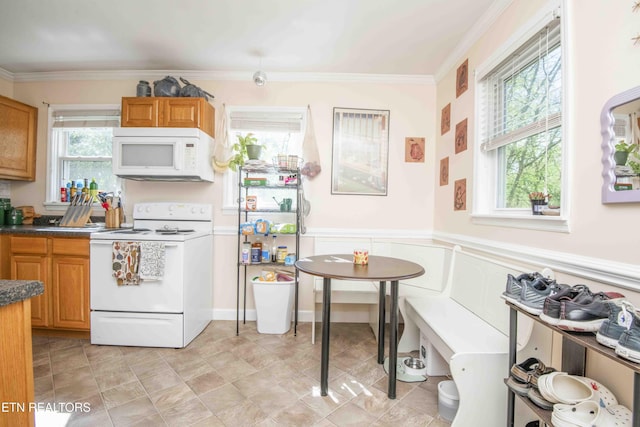 kitchen featuring ornamental molding, dark countertops, white appliances, brown cabinets, and a wainscoted wall