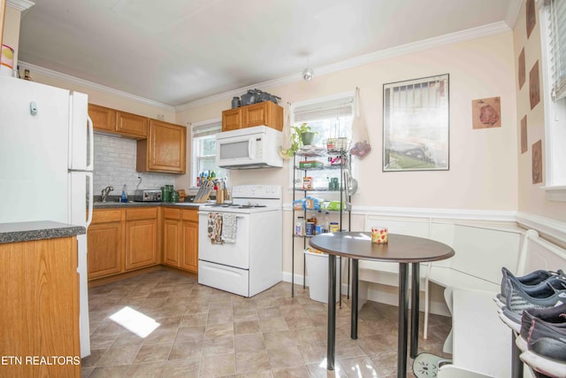 kitchen featuring ornamental molding, white appliances, dark countertops, wainscoting, and decorative backsplash