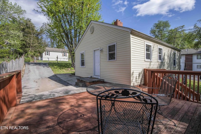 rear view of property with a chimney, a wooden deck, fence, and a patio area